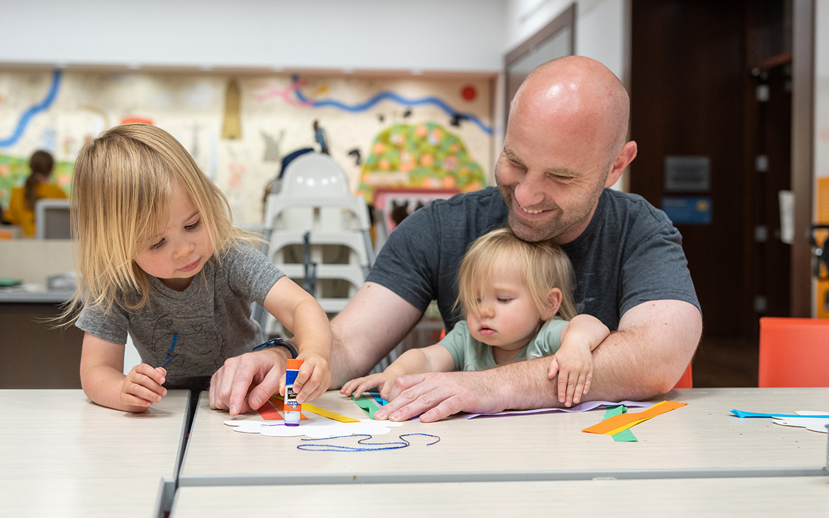 A white father makes art with his two young daughters.