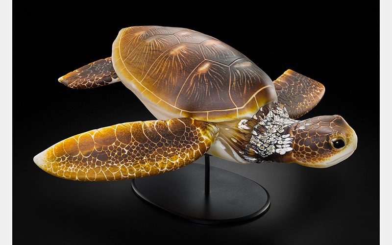 A light yellow turtle made from glass with intricate scales and shell