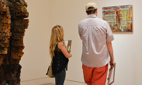 Two visitors look at a work together in a gallery