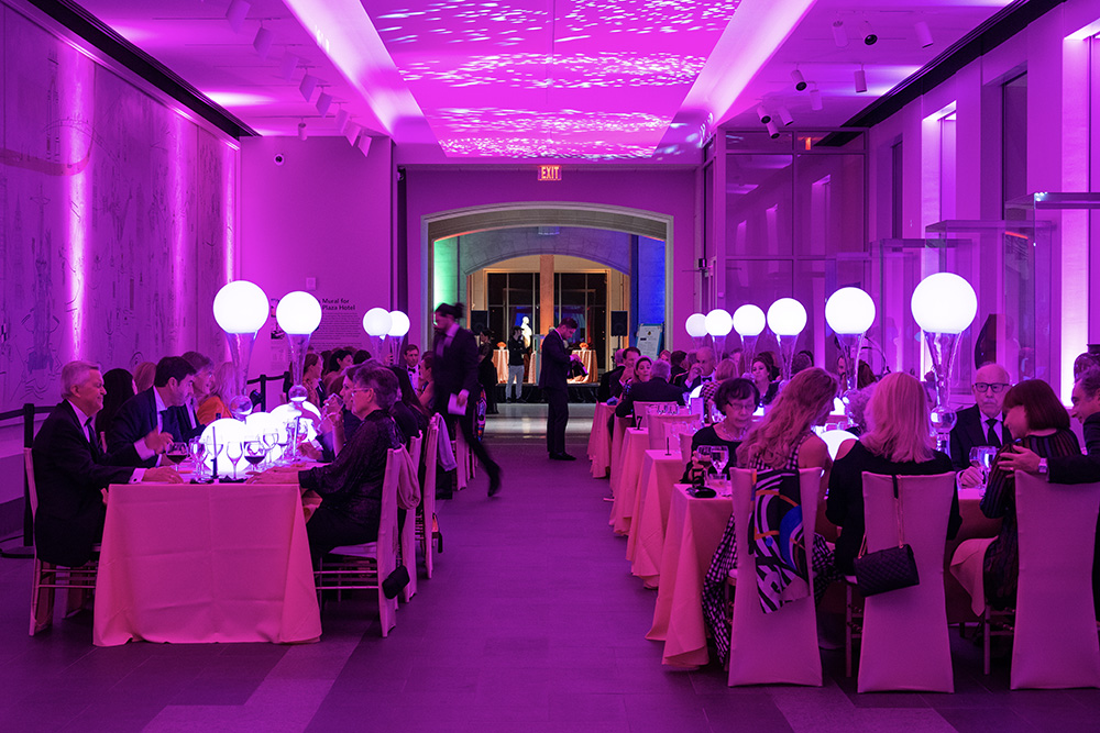 Visitors enjoy a seated dinner in a purple-lit hallway