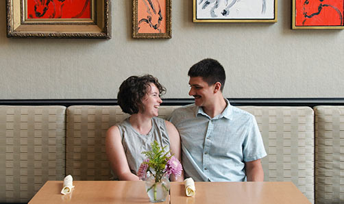 A white couple laugh at a table in the Cafe