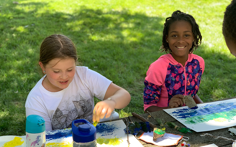 Kids work on art at a park bench