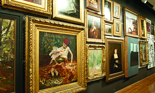 A gallery wall featuring many paintings