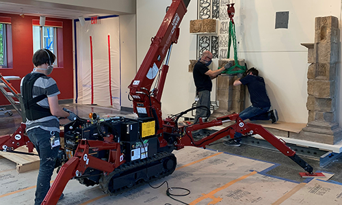 CAM staff install large blocks of a shrine using a large mechanical lift