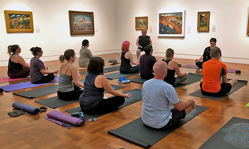 Visitors sit on yoga mats in a gallery