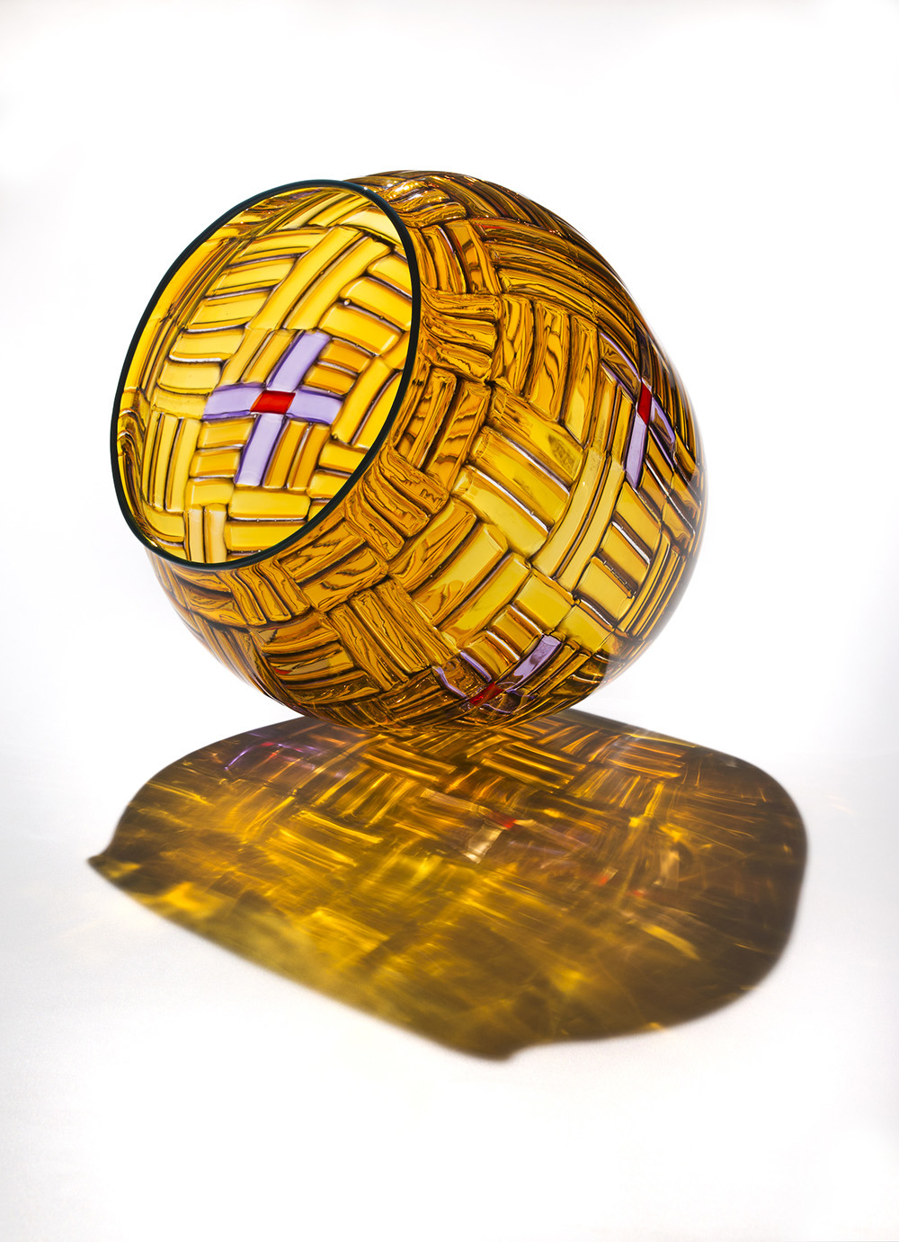 Aunt Fran’s Star Basket is a three-dimensional blown glass vessel. This basket, made of glass, sits on a rounded bottom. It has straight sides and a wide mouth.