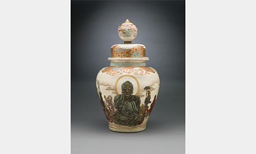 An ornate, light-colored vase featuring a design of Buddha
