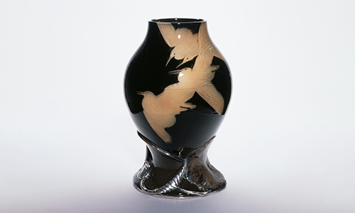 A black glass vase with gold colored birds