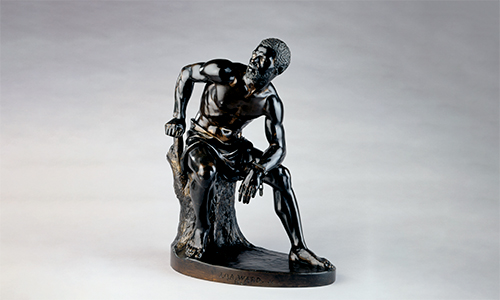 A shiny, dark sculpture of a sitting man.