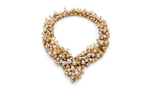 A gold necklace with many overlapping pearls
