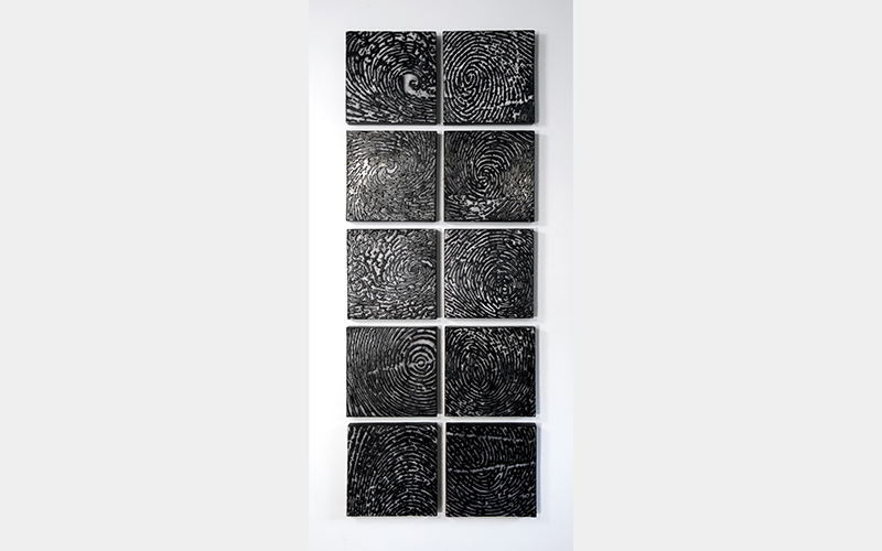 A series of nine dark, square panels mounted in two tight columns