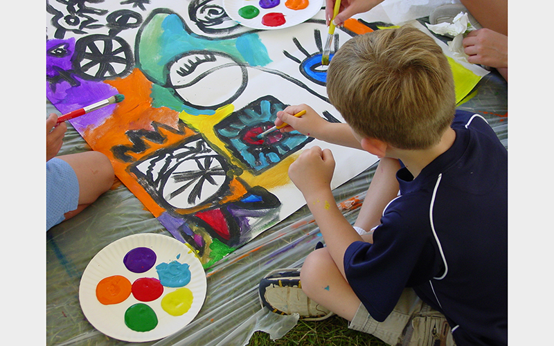 A young kid contributes to a group painting