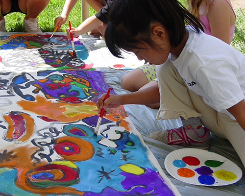 A young child works on a group painting outside