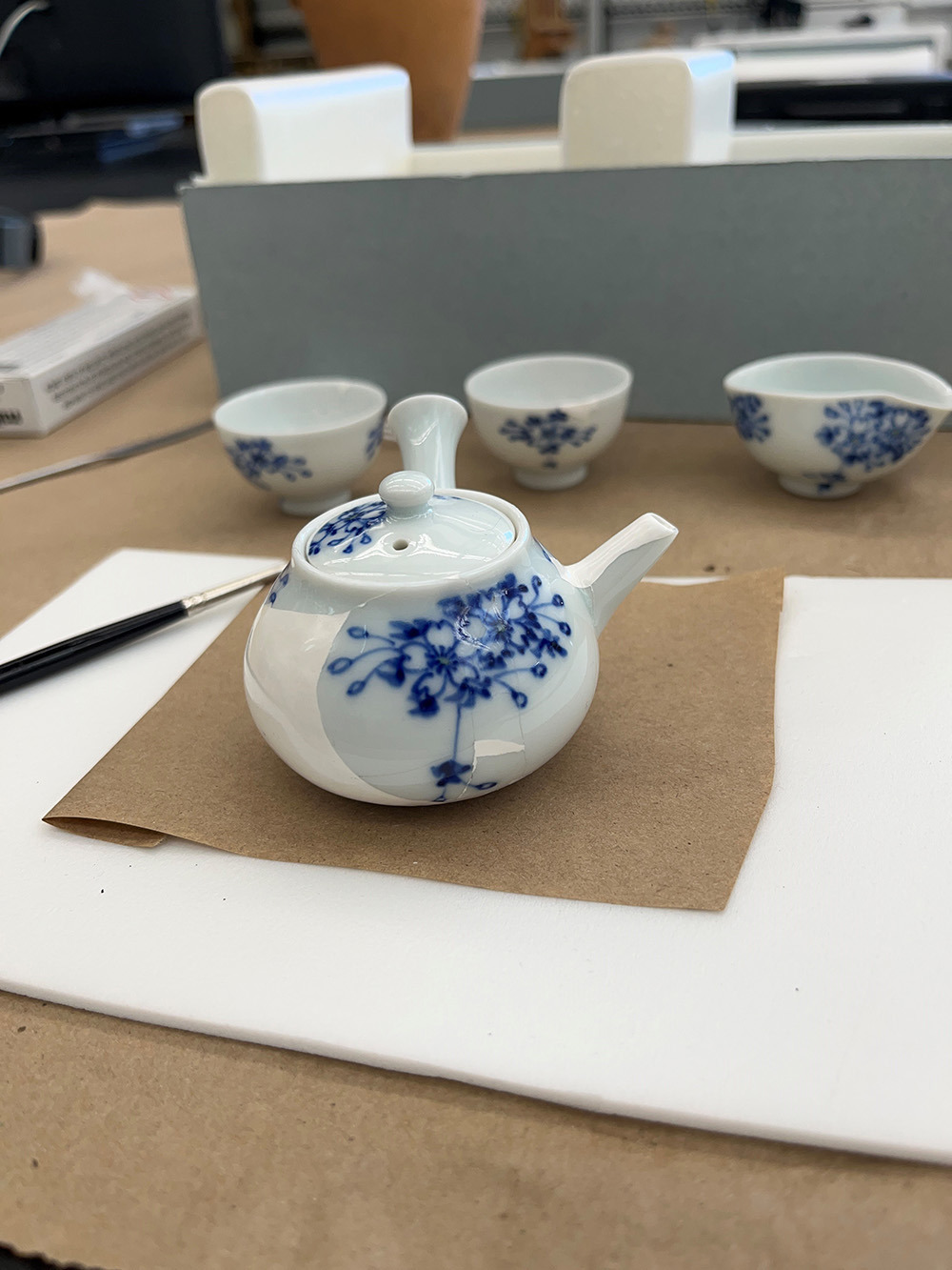 A small white teapot with blue floral decorations