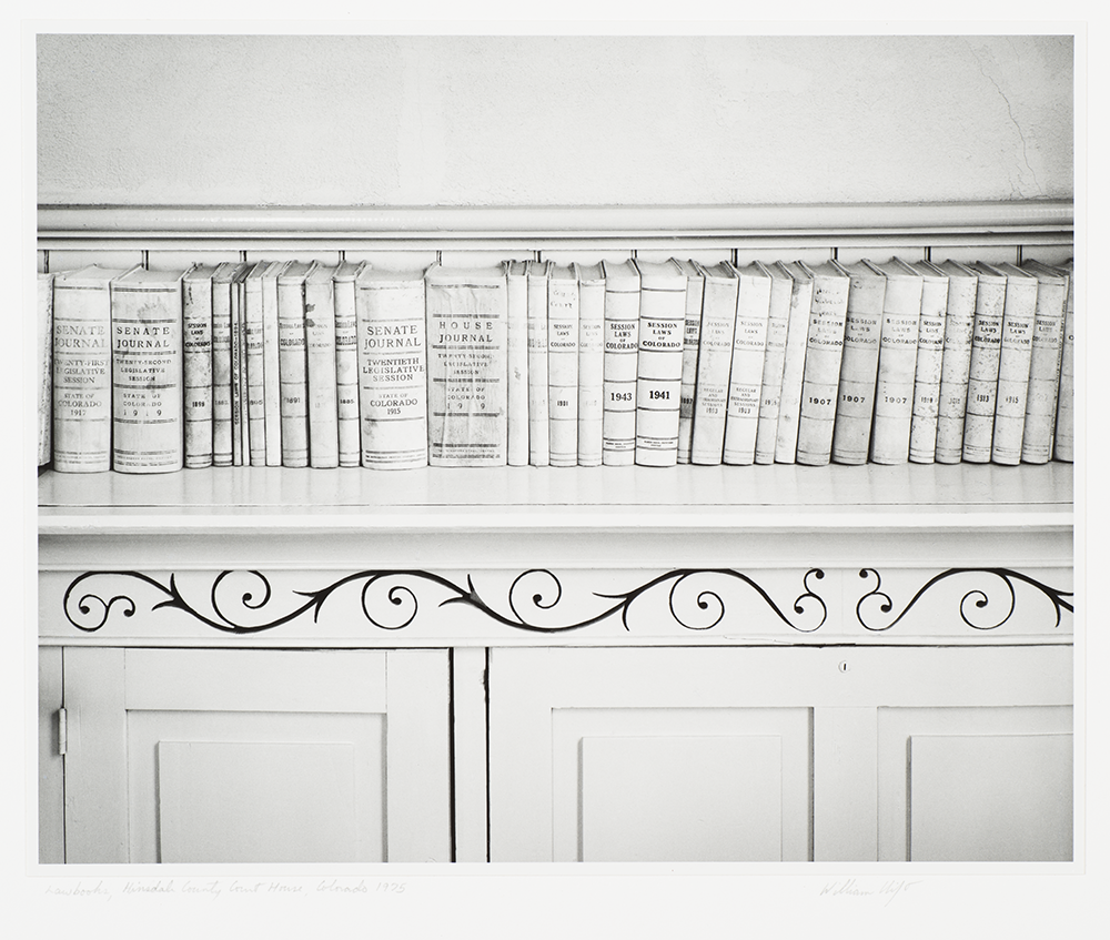 Black and white photograph of old books lined on a shelf