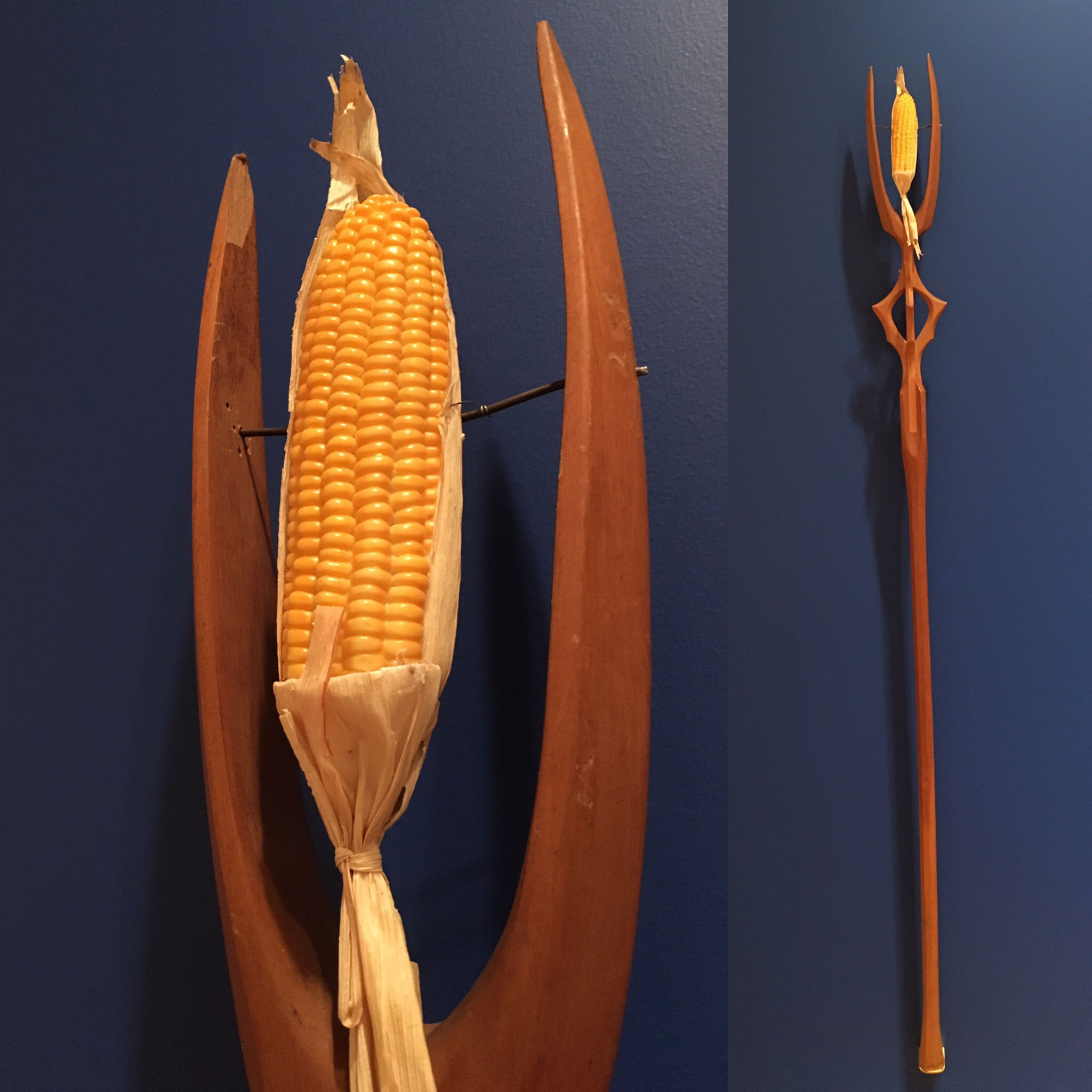 A forked wooden staff adorned with an ear of corn at the tip