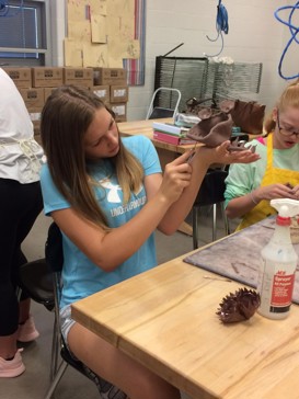 student carving out clay sturcture