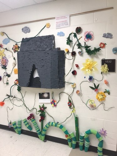 art project made of paper flowers ad plastic cups hung in a school hallway