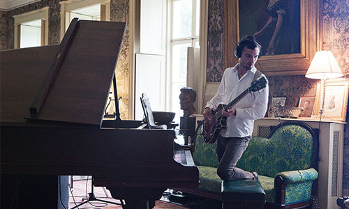 man playing a guitar next to a piano