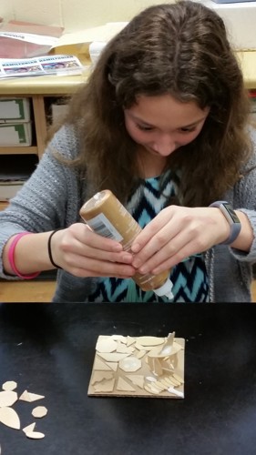 student glueing pieces together