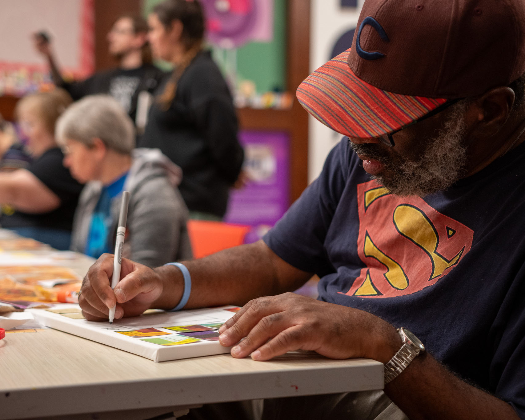 A Black man colors on a canvas during a workshop
