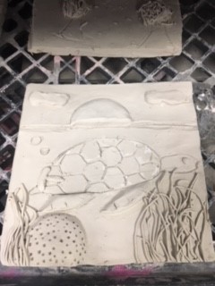 clay tile of a sea turtle swimming through coral