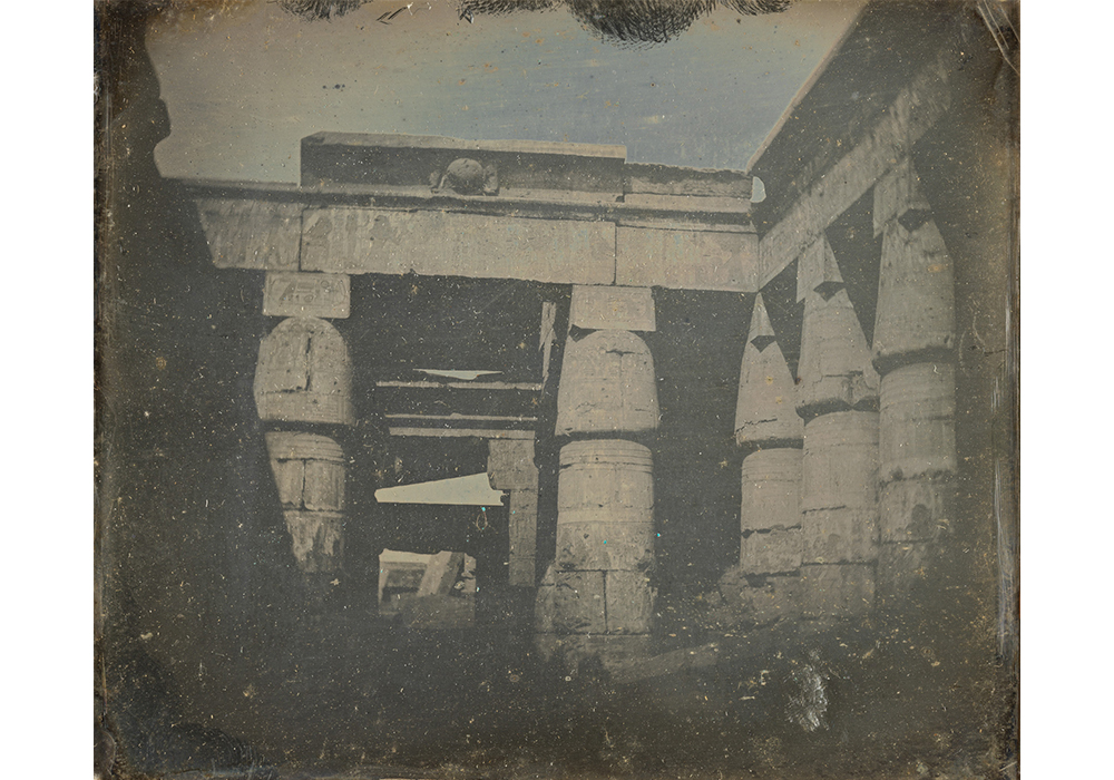 Old black and white photograph of the courtyard in an Egyptian temple with towering, round pillars
