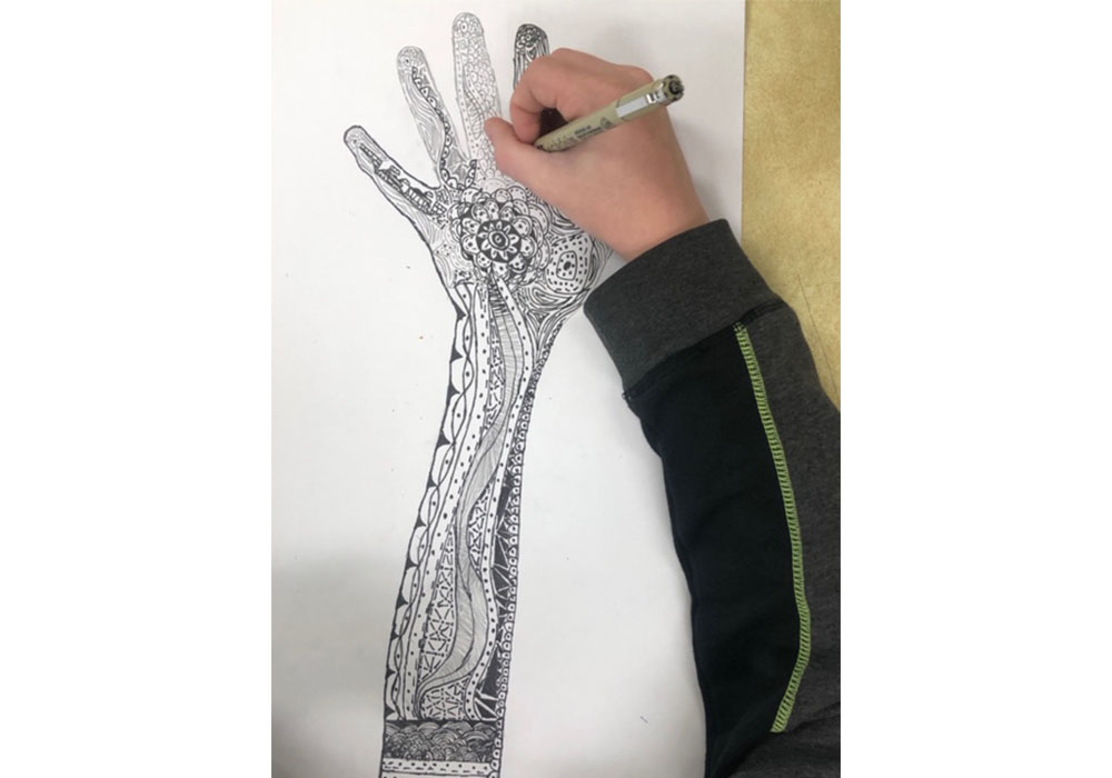student drawing an intricately decorated arm