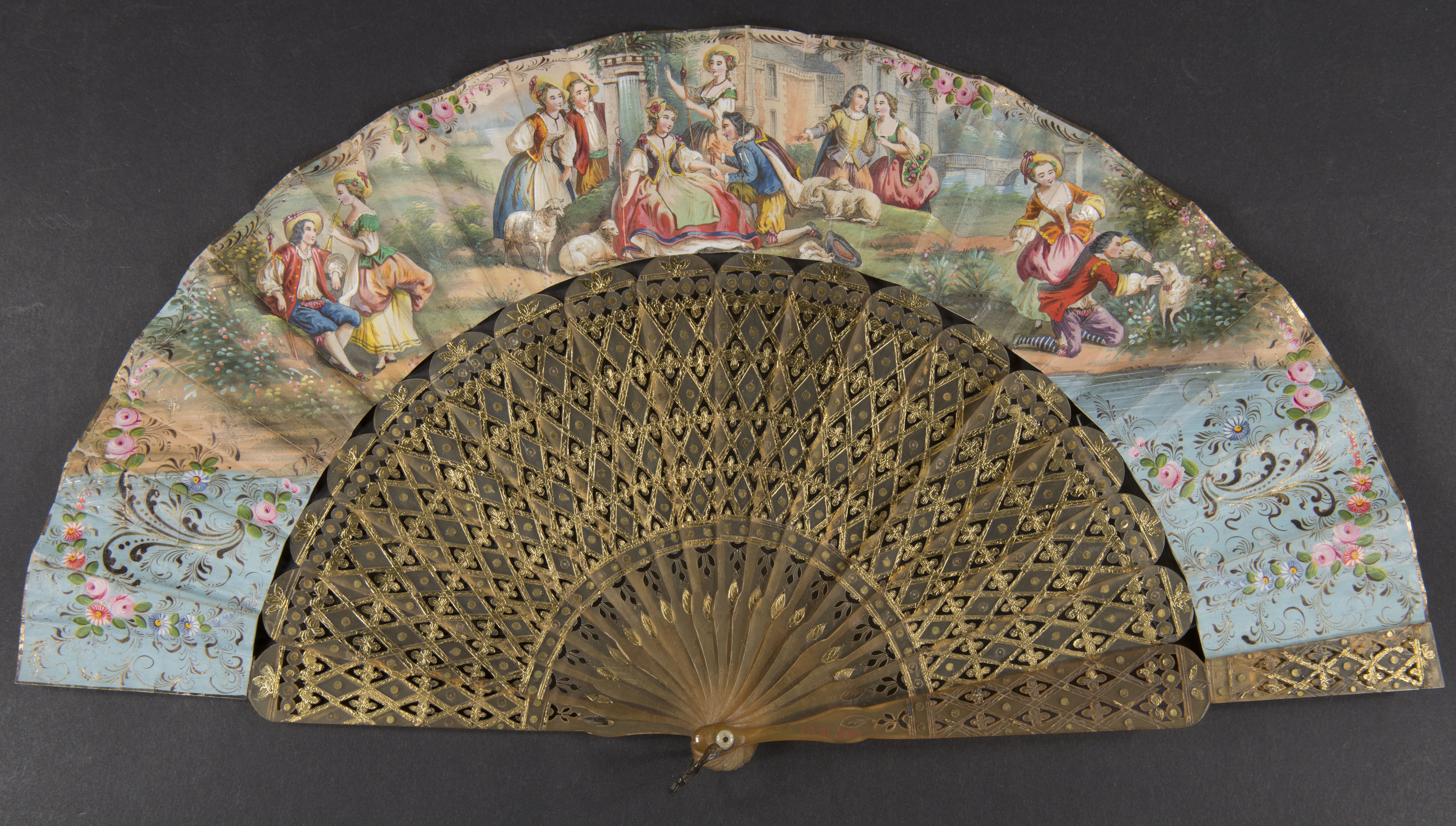 hand fan with painting of ornate flowers and scenes from upper class Victorian life