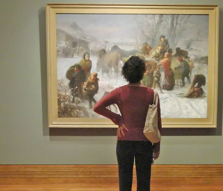 visitor inspects a painting in a gallery