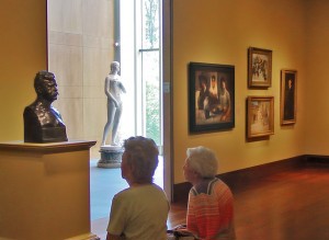 visitors inspect a bronze bust in a gallery