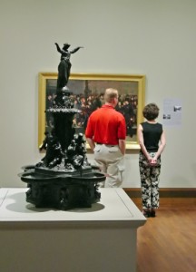 visitors inspect a painting in a gallery
