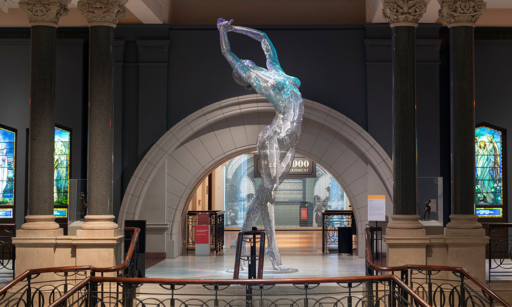 A large statue of a ballerina placed at the top of the Great Hall staircase in the Cincinnati Art Museum