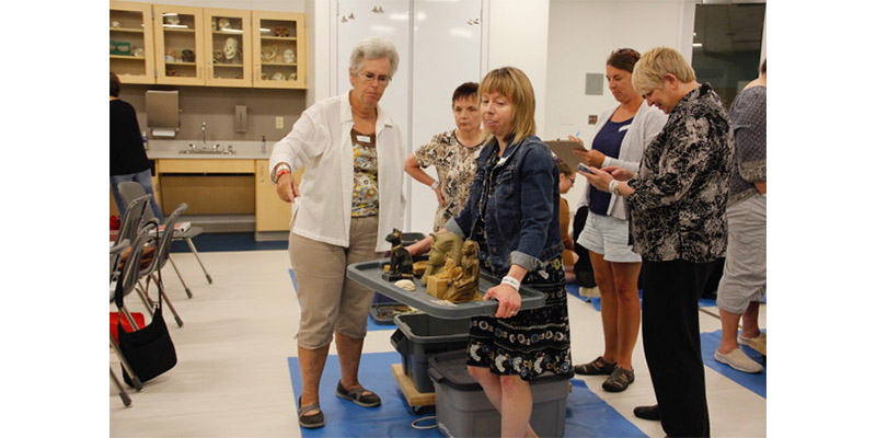 A group of teachers, one carrying various Egyptian artifacts