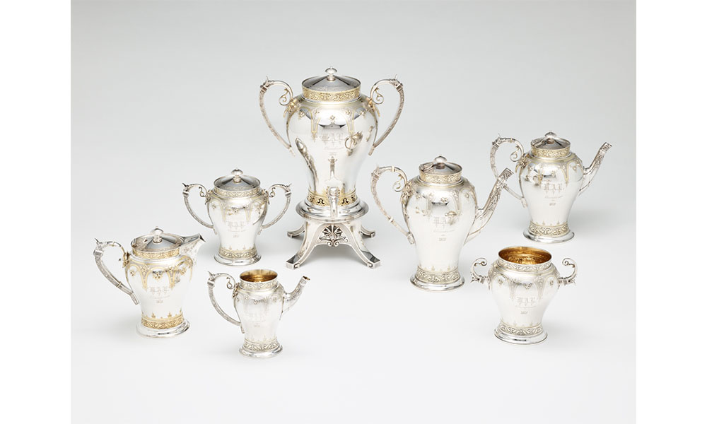 Silver and gold coffee pots, tea pots, drink dispensers, all with curved handles and ornate etchings