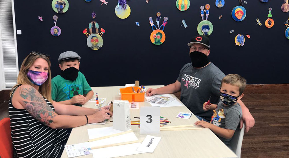 Family wears masks working on arts and crafts
