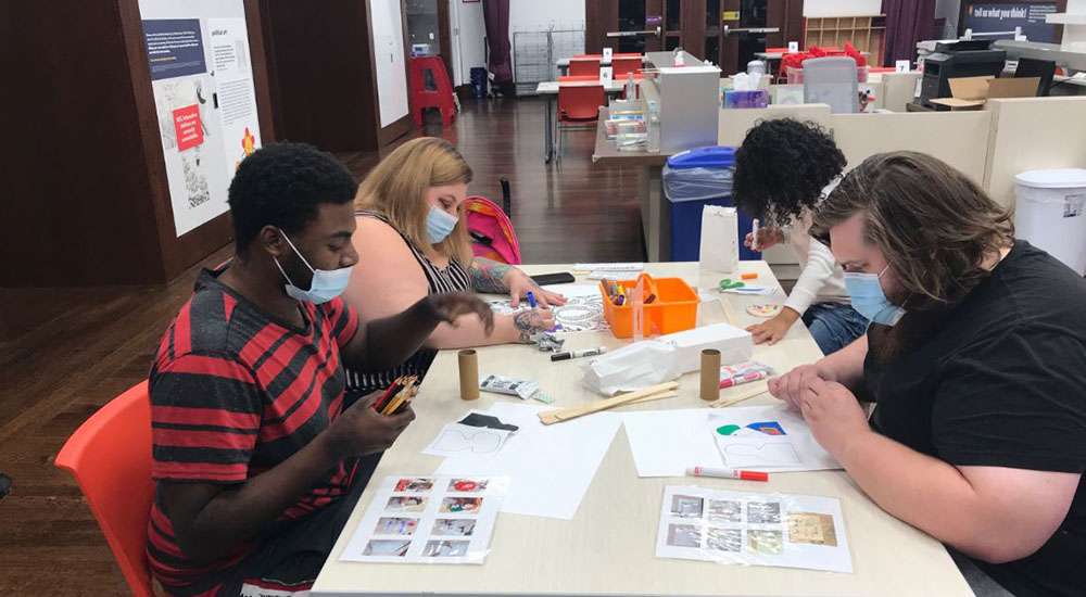 Visitors wear masks working on arts and crafts