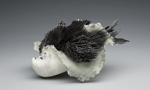 a glazed sculpture of flowing white petals surrounding hundreds of black, coral like stems seemingly blowing in the wind