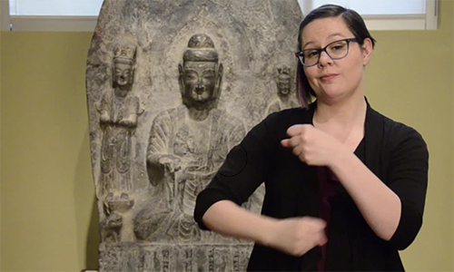 ASL interpreter in front of a stone statue