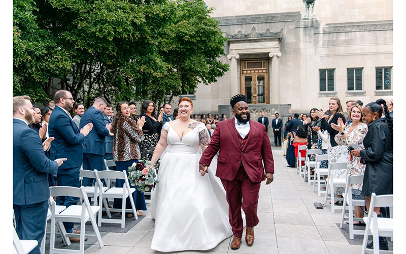 A couple walks down the aisle in the courtyard