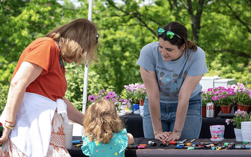 A mother and child visit a booth outside