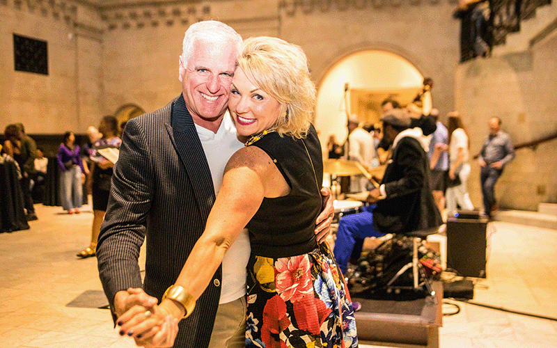 A smiling white couple pose for the camera while dancing