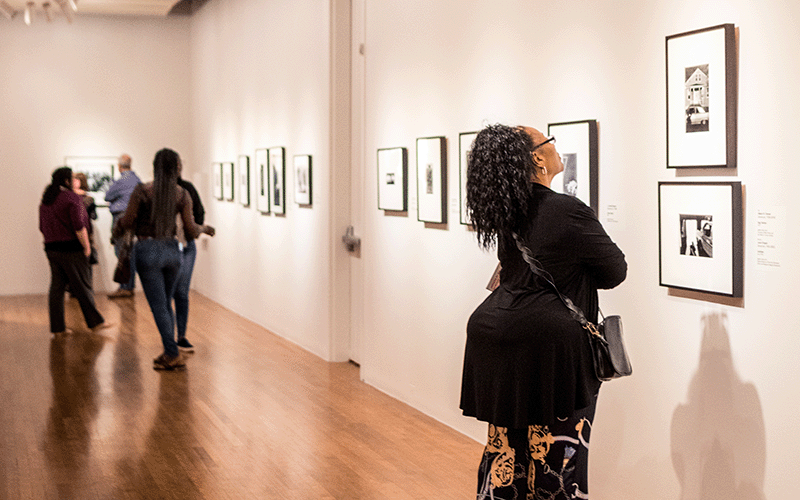 A Black woman looks at artworks on a wall