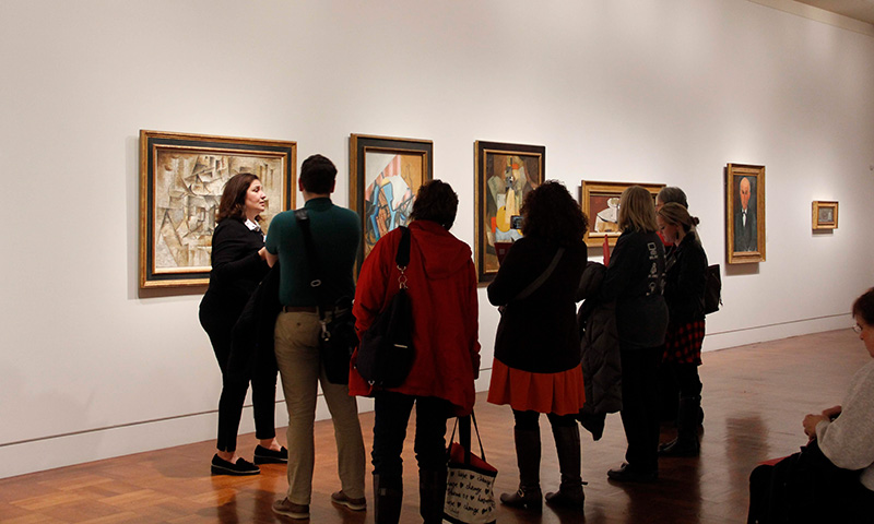 A group of visitors listen to a docent-led public tour at the Cincinnati Art Museum