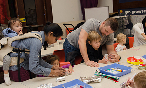 Parents help their young kids with an art activity