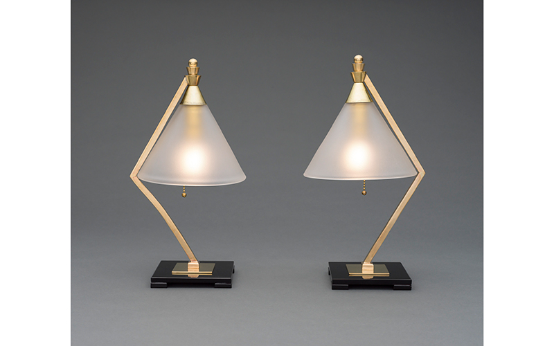 Two desk lamps with brass, skinny, angled stems, triangular frosted glass shades, and square black glass bases.
