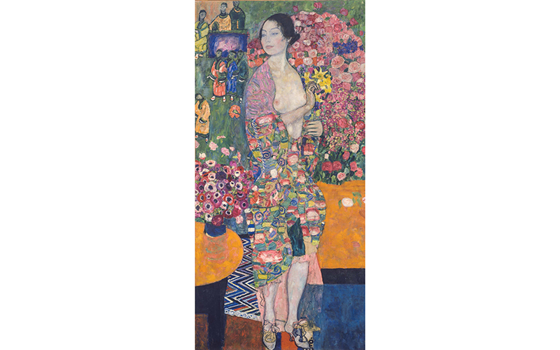 A painting by Gustav Klimt of a bare-breasted young woman looking to the side and wearing a colorful robe. She holds daffodils and stands in front of a colorful mural depicting flowers and men in robes.