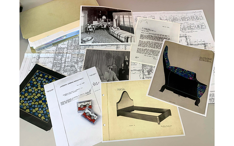 Documents with images of furniture, blueprints, and archival photos of the room laid out on a table.