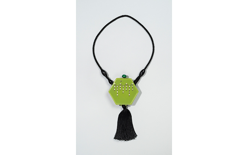 Black and light green hexagon-shaped compact with long twisted black cord and tassel. 