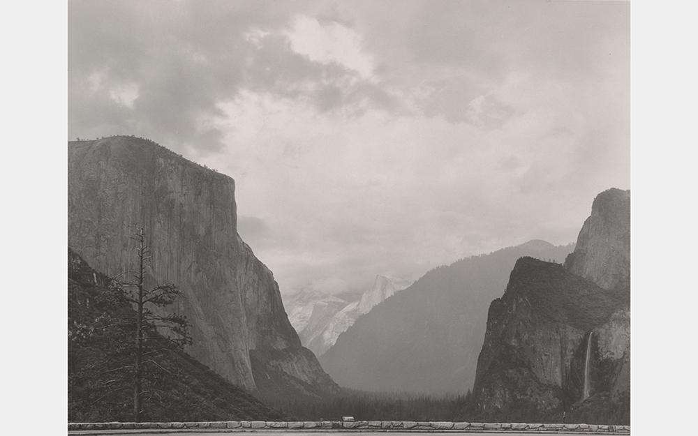 A black and white photo of a valley between big mountains